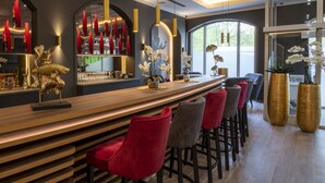 Un área de bar moderna con mostrador de madera, taburetes de bar rojos y grises, y detalles decorativos como una escultura de pez y orquídeas.