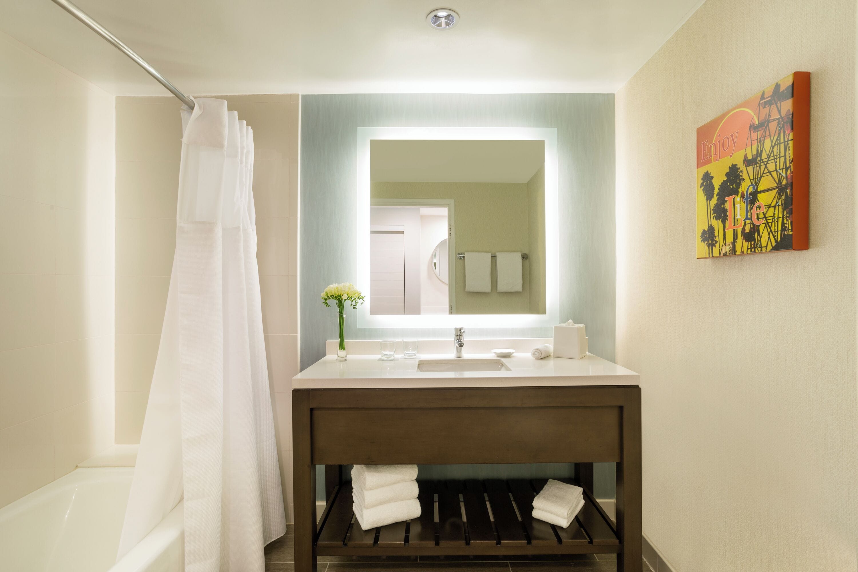 A modern bathroom with a shower curtain, a sink with a mirror, and a towel rack.