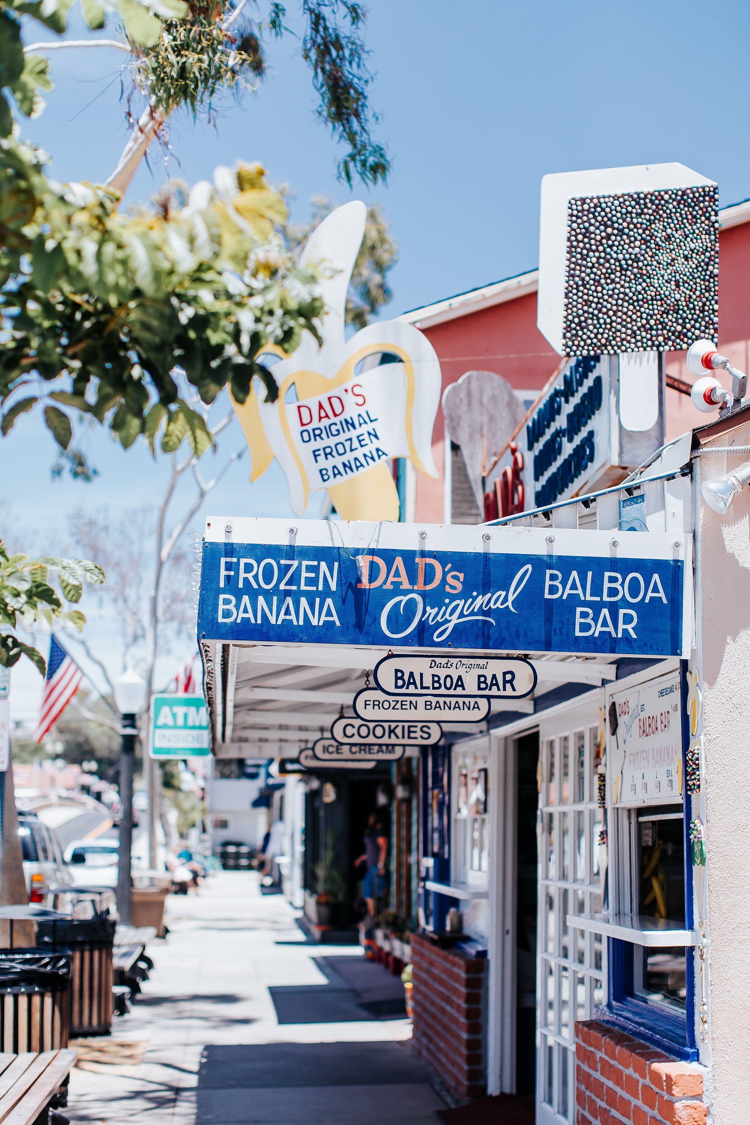 Uma fachada com um letreiro anunciando 'Frozen Dad's Original Balboa Bar' e 'Banana Gelada Original do Dad'.
