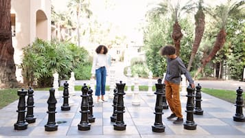 A chessboard set outdoors with two people standing on it.