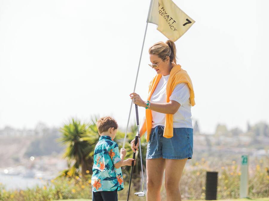A golf course with a flag marked "HYATT REGENCY" and a person standing with a golf club.