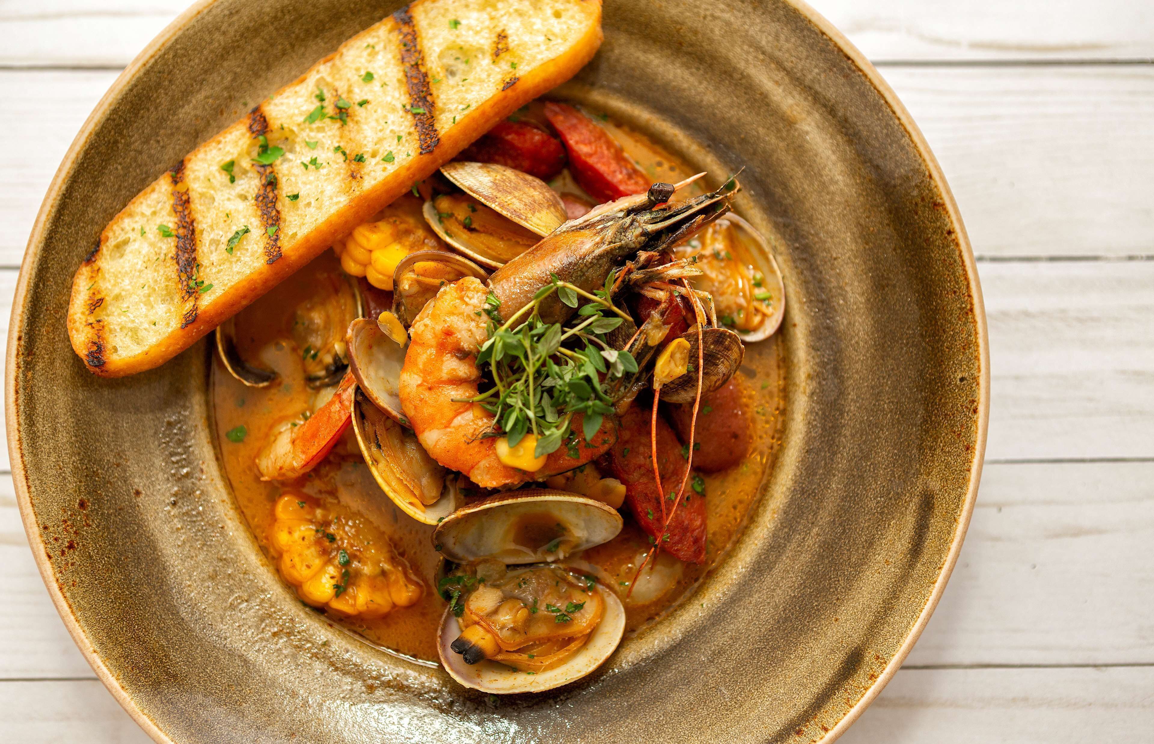 A seafood dish with bread on a ceramic plate.