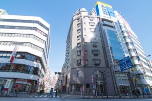 Hotel Strix Tokyo features a striking facade with a mix of glass and solid materials.