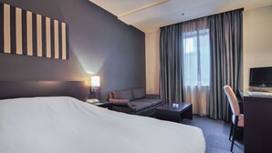 A hotel room with a large bed, a sofa, a desk, and a TV. - Hotel Strix Tokyo (Tokyo)