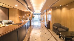 A hotel lobby with a reception desk, a seating area, and a hallway leading to the entrance. - Hotel Strix Tokyo (Tokyo)