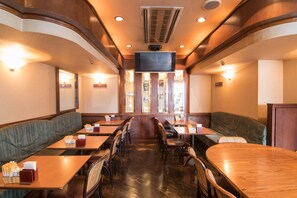 Enjoy a classic dining experience with booths and tables, a central TV screen, and comfortable seating.
