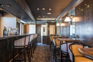 A bar area with a patterned carpet, wooden bar counter, and multiple chairs and tables. - Hotel Strix Tokyo (Tokyo)
