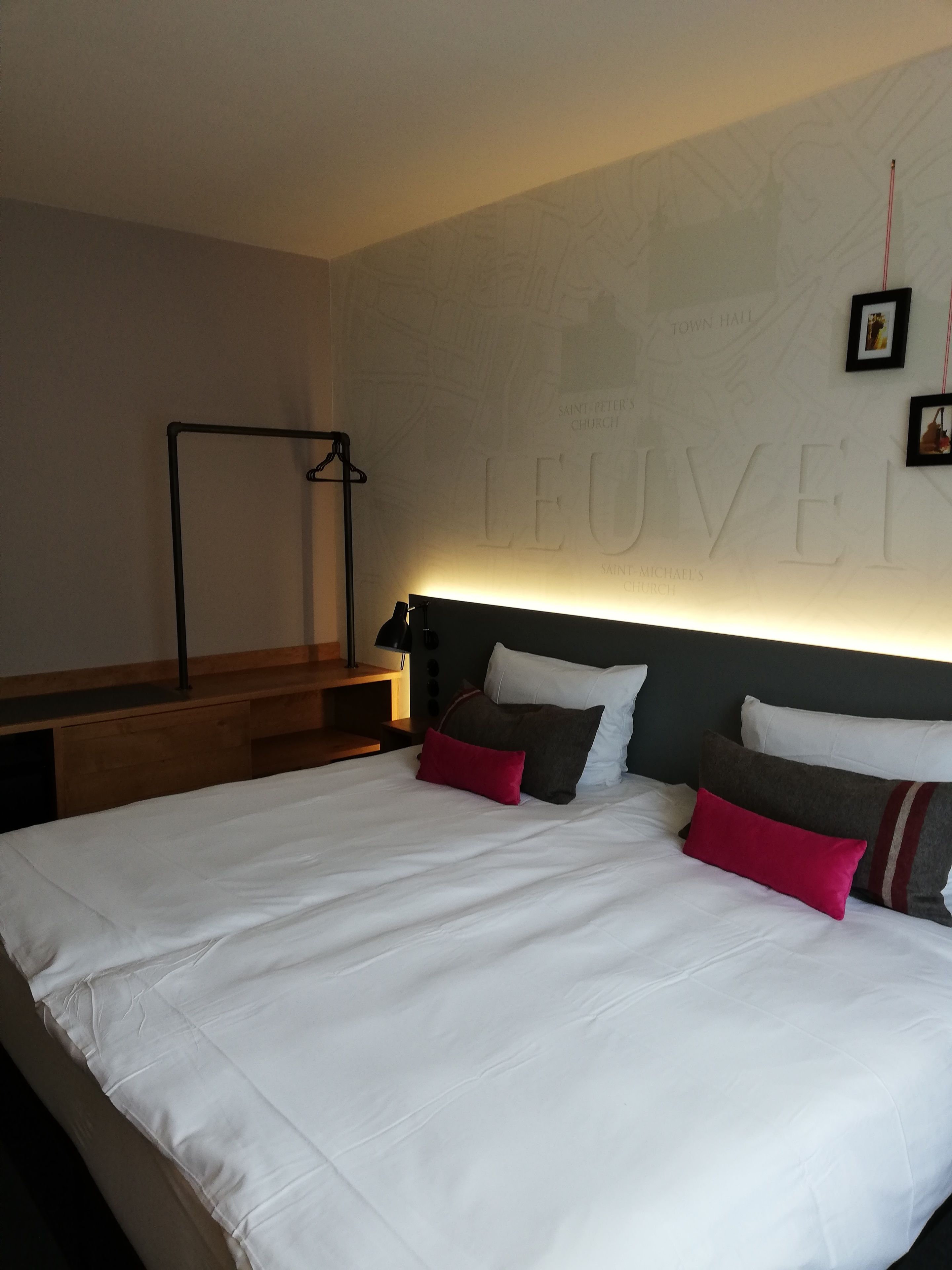 Una habitación de hotel con una cama grande, un cabecero con un mapa y un escritorio con una lámpara.