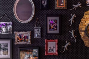 A wall with various framed pictures and decorative items, including a mirror and lizards. - pentahotel Leuven (Leuven)