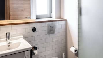Une salle de bain moderne avec un lavabo blanc, des toilettes et une fenêtre située au-dessus du lavabo.