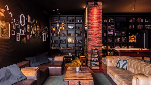 Un rincón de sala acogedor con sofás de cuero, una mesa de centro de madera y una estantería llena de libros y objetos decorativos.