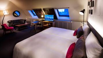 Een moderne hotelkamer met een groot bed, een bureau, een sofa en dakramen.