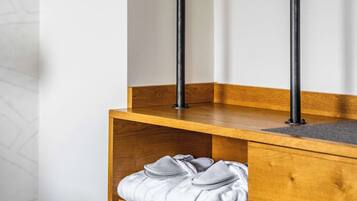 Esquina de una habitación con un banco de madera y un perchero de metal negro.