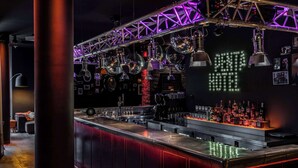 Una zona de bar con una barra larga, múltiples bolas de discoteca colgantes y un letrero de neón en la pared.