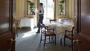 A dining area with a table set for four, a waiter, and two potted plants. - Hartwell House & Spa (Aylesbury)