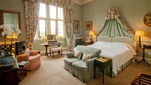 A bedroom with a four-poster bed, a desk, a chair, and a small table with lamps. - Hartwell House & Spa (Aylesbury)