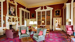 A library with bookshelves, a fireplace, and seating areas. - Hartwell House & Spa (Aylesbury)