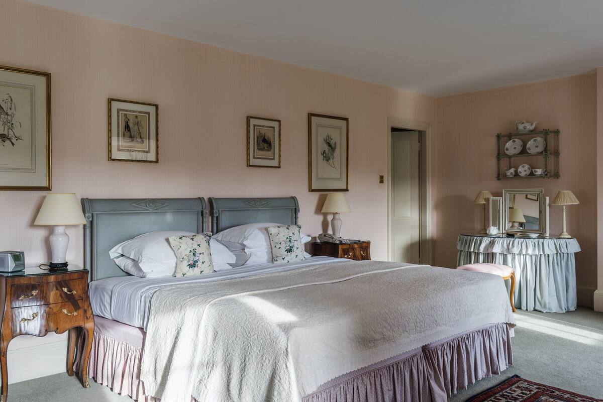 A bedroom with a large bed, two bedside tables, a dresser, and framed artwork on the walls.