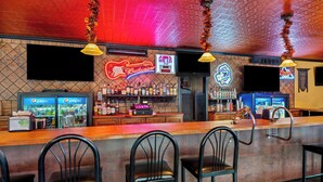 A bar area with a counter, bar stools, and a neon sign for Budweiser.