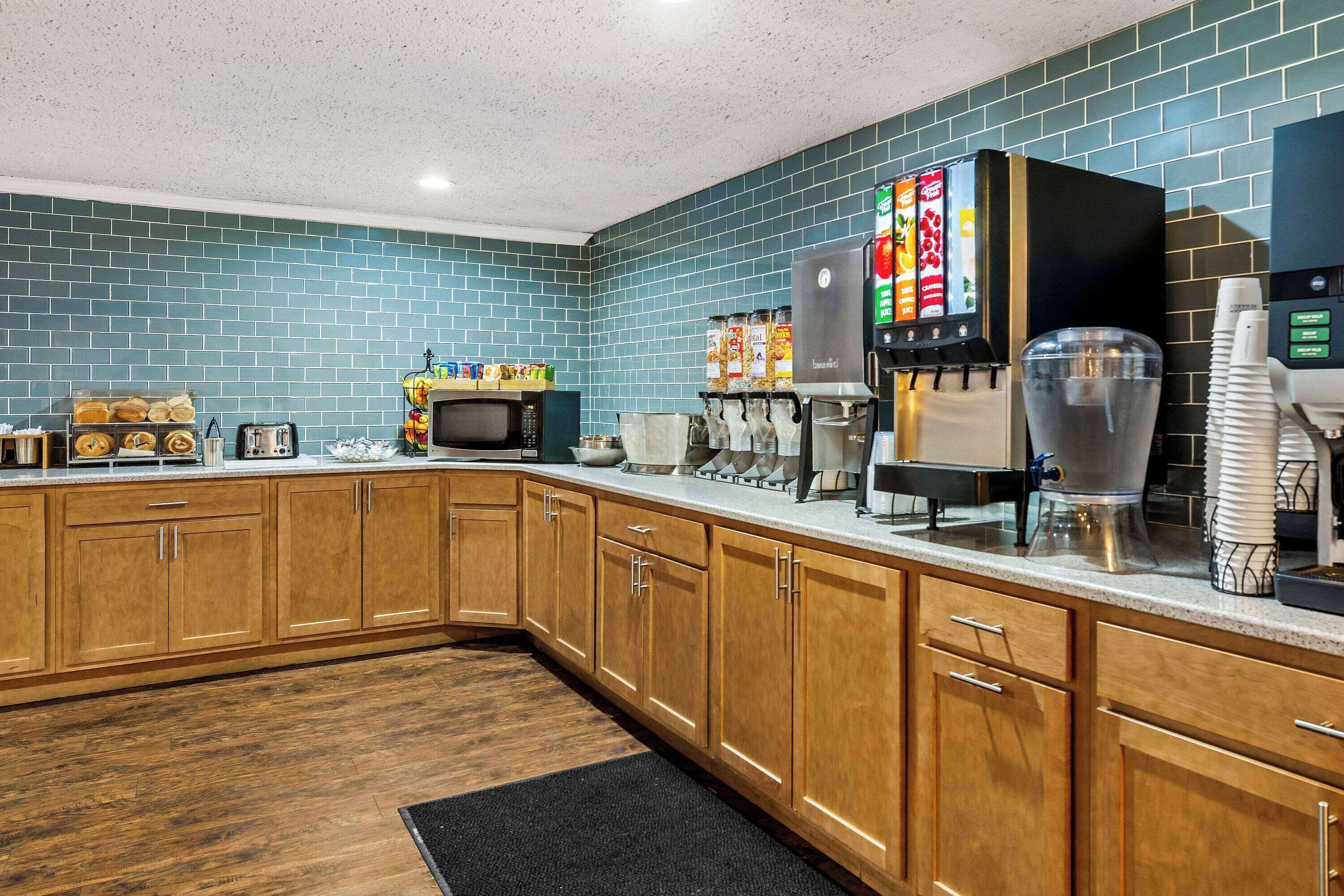 A kitchen with wooden cabinets, a microwave, a coffee machine, and a beverage dispenser.