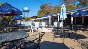 An outdoor patio area with tables and chairs, a fire pit, and umbrellas branded with Samuel Adams.