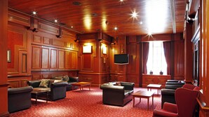 A spacious room with wooden paneling, leather sofas, and a red carpet. - The Royal Hotel Hull (Hull)