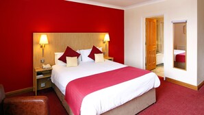 A hotel room with a large bed, red walls, and a wooden headboard. - The Royal Hotel Hull (Hull)