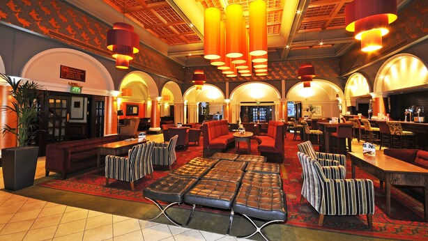 A spacious lobby with a central seating area, multiple tables, and a high ceiling with ornate lighting fixtures. - The Royal Hotel Hull (Hull)