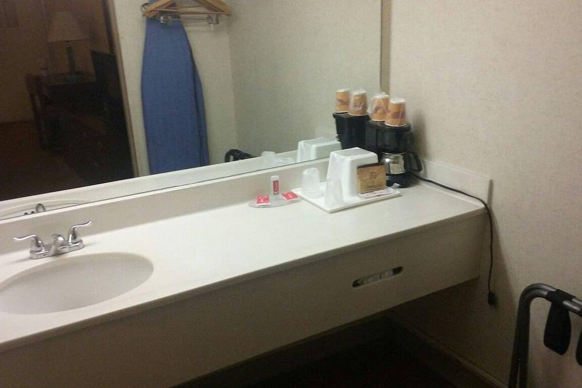 A hotel bathroom with a sink, mirror, and toiletries.