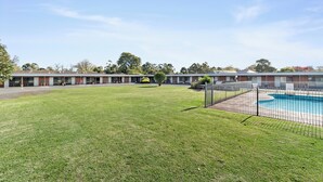 A motel with a swimming pool, a well-maintained lawn, and a row of rooms with a uniform exterior. - Baronga Motor Inn (Colac)