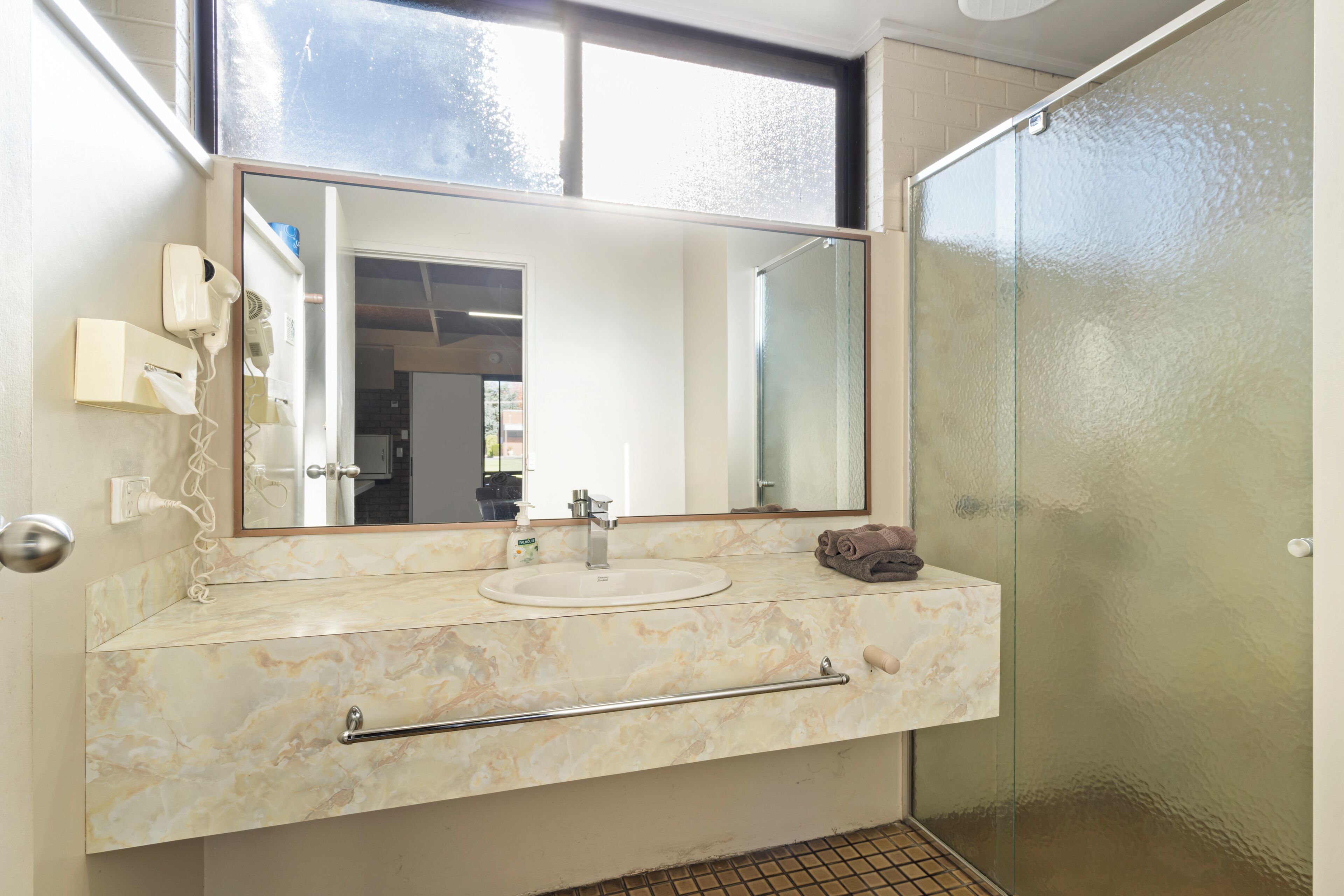 A bathroom with a marble vanity, a glass shower enclosure, and a large mirror.