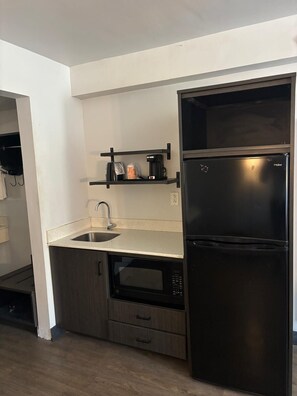 A compact kitchen with a built-in microwave, a stainless steel sink, and a black refrigerator. - Clarion Pointe (Dublin)