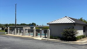 A parking lot with a gated entrance, a small building with a metal roof, and a clear blue sky. - Clarion Pointe (Dublin)