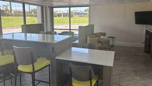 A modern conference room with a large table and chairs, large windows with a view of a building and greenery, and a flat-screen TV mounted on the wall. - Clarion Pointe (Dublin)