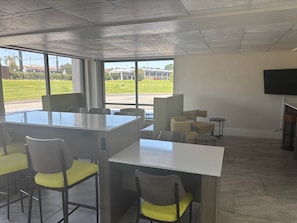 A modern conference room with a large table and chairs, large windows with a view of a building and greenery, and a flat-screen TV mounted on the wall. - Clarion Pointe (Dublin)
