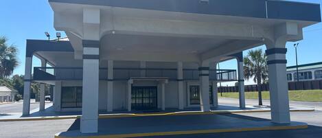 A gas station with a covered canopy, multiple fuel pumps, and a security camera.