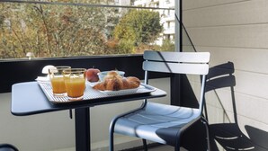 Un balcón con una mesa dispuesta para el desayuno, que incluye croissants, fruta y zumo de naranja.