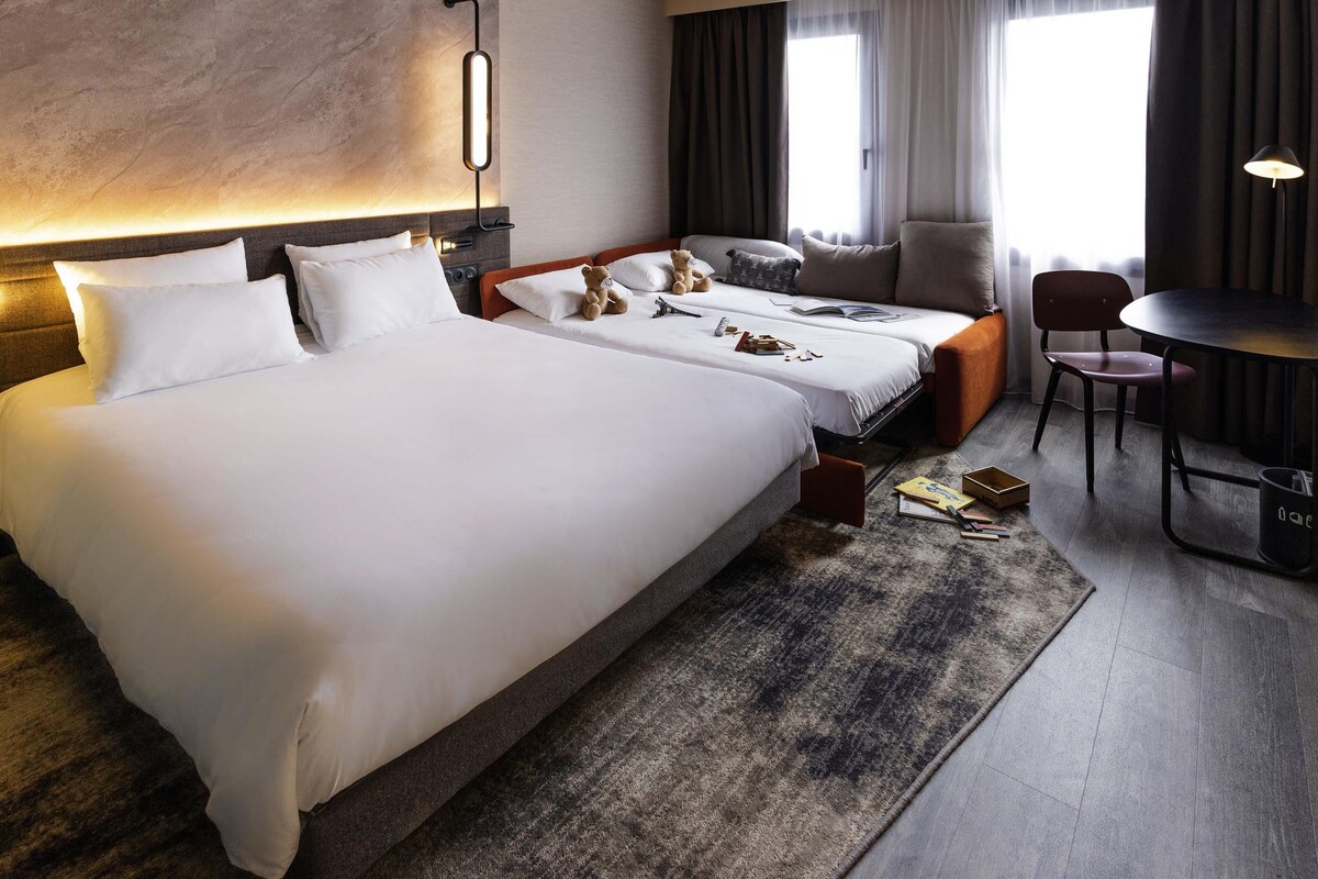 A hotel room with two beds, a desk, and a chair.