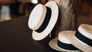 Twee stroohatten rusten tegen een houten paal.