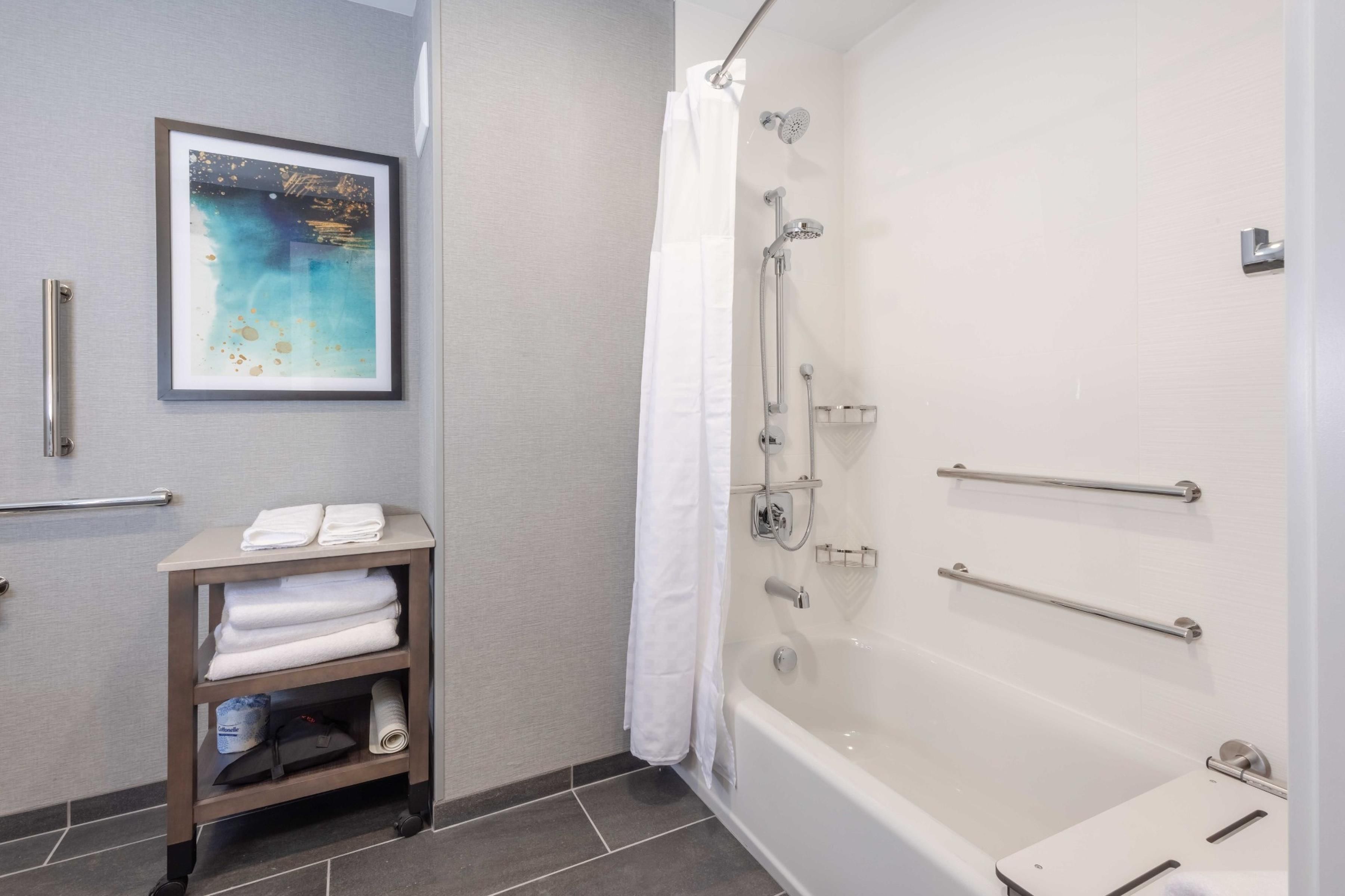 A bathroom with a bathtub, a shower, a towel rack, and a framed picture on the wall.