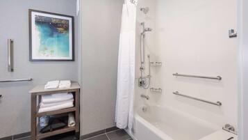 A bathroom with a bathtub, a shower, a towel rack, and a framed picture on the wall.