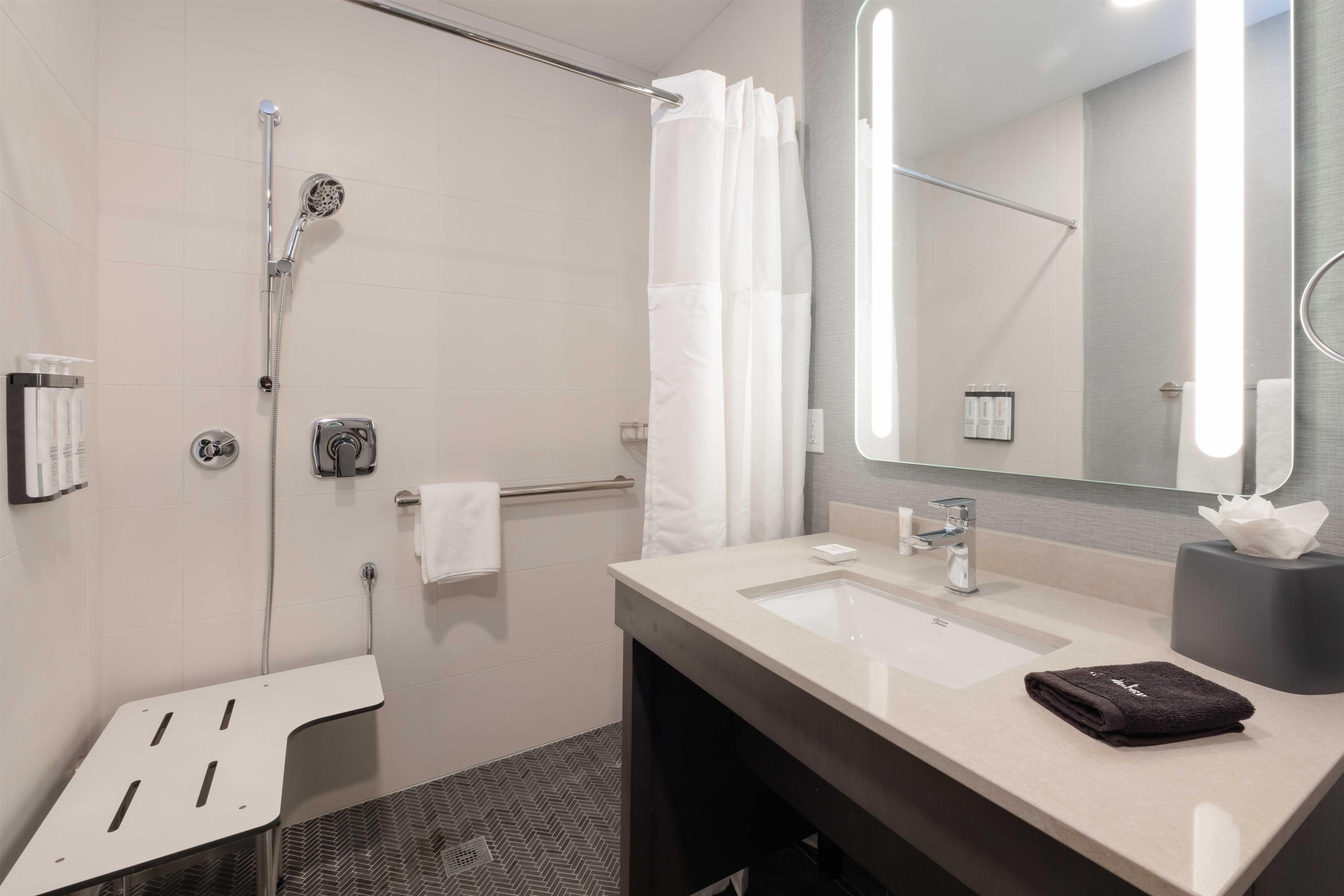 A modern bathroom with a shower, a sink, a mirror, and a towel rack.