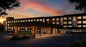 A modern hotel with a covered entrance, multiple floors, and a parking lot.