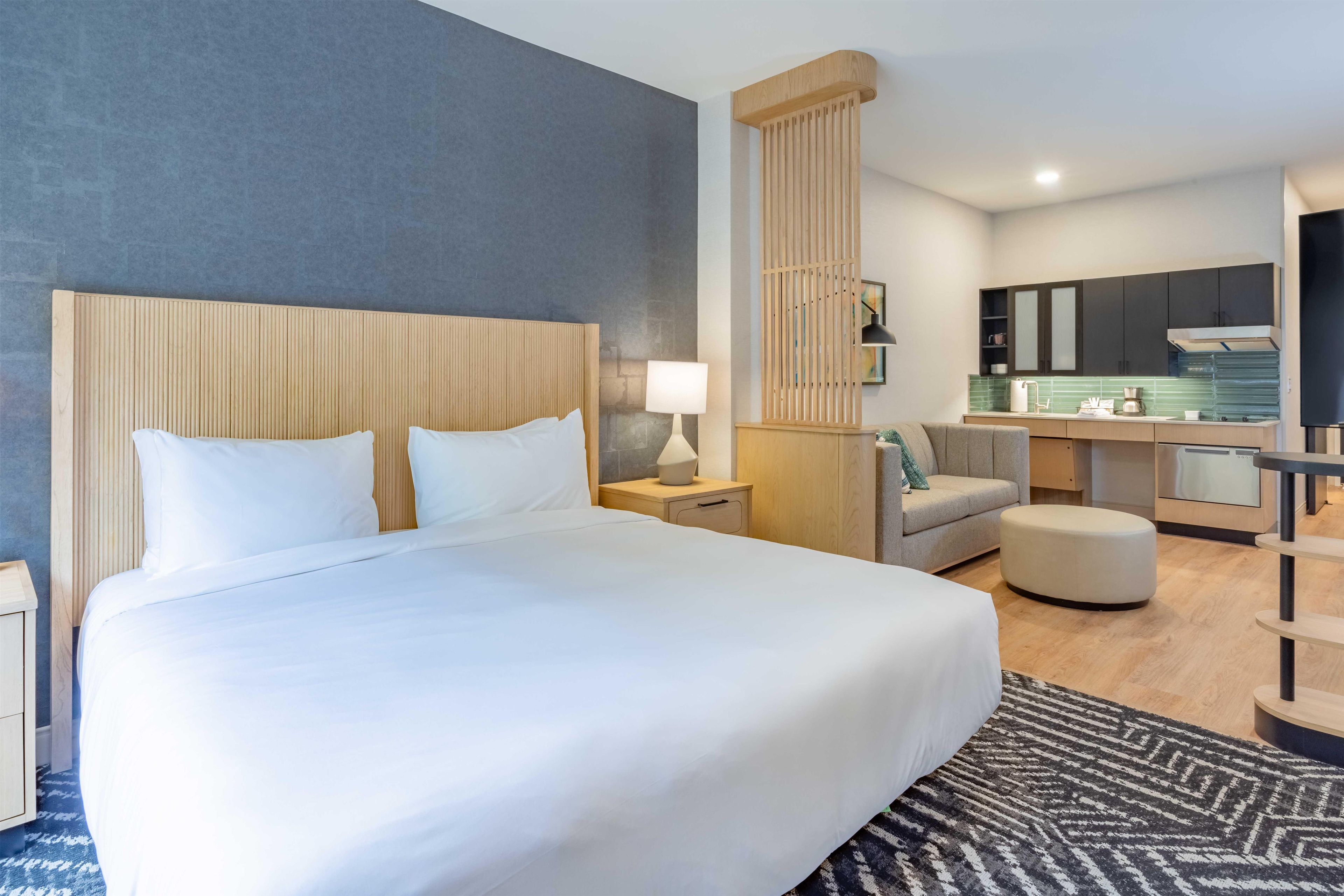 Een hotelkamer met een groot bed, een bureau, een stoel, een bank en een kitchenette.