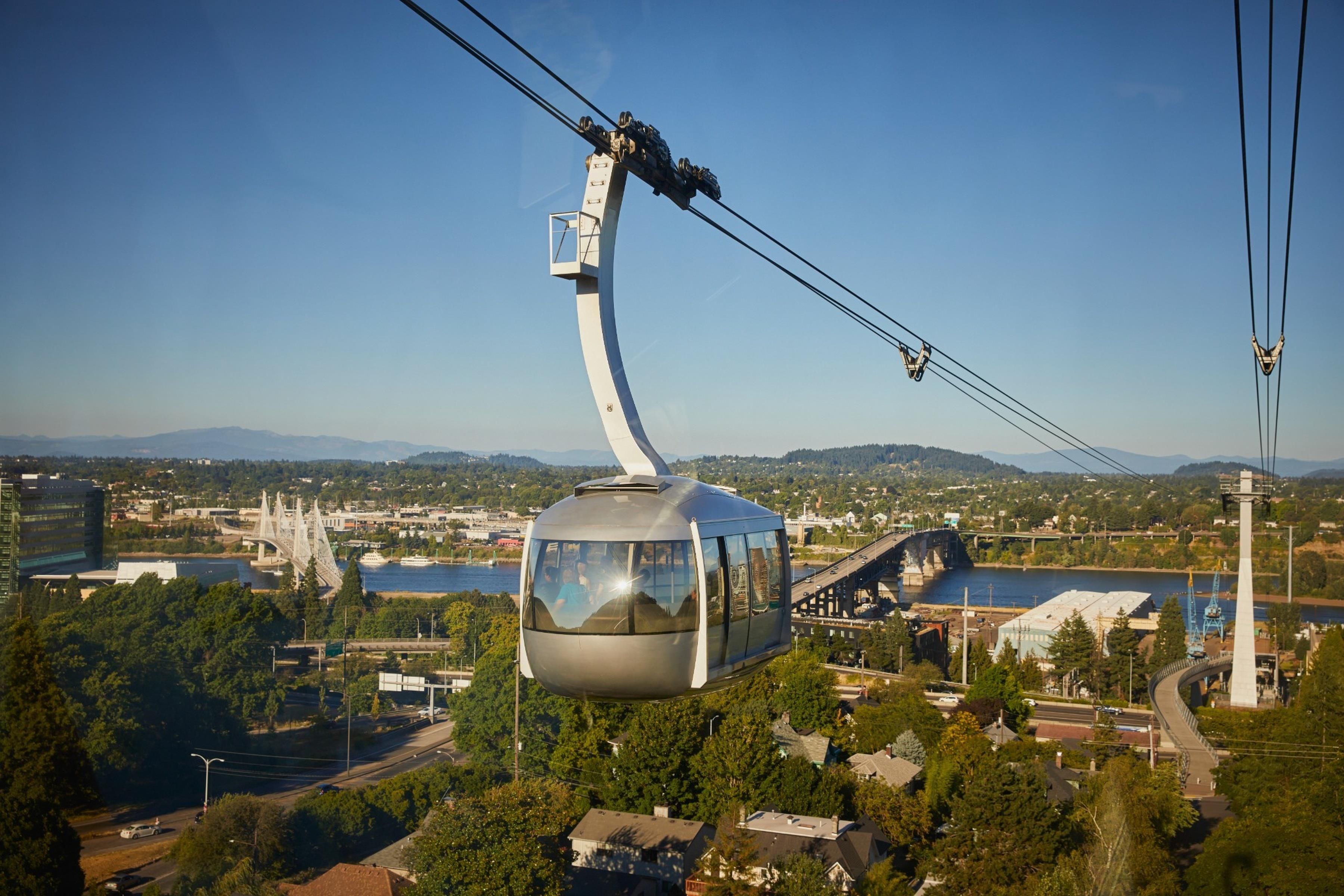 A cable car system with a curved cable, a bridge, and a cityscape in the background.