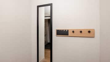 A mirror with a black frame and a wooden coat rack with hooks.