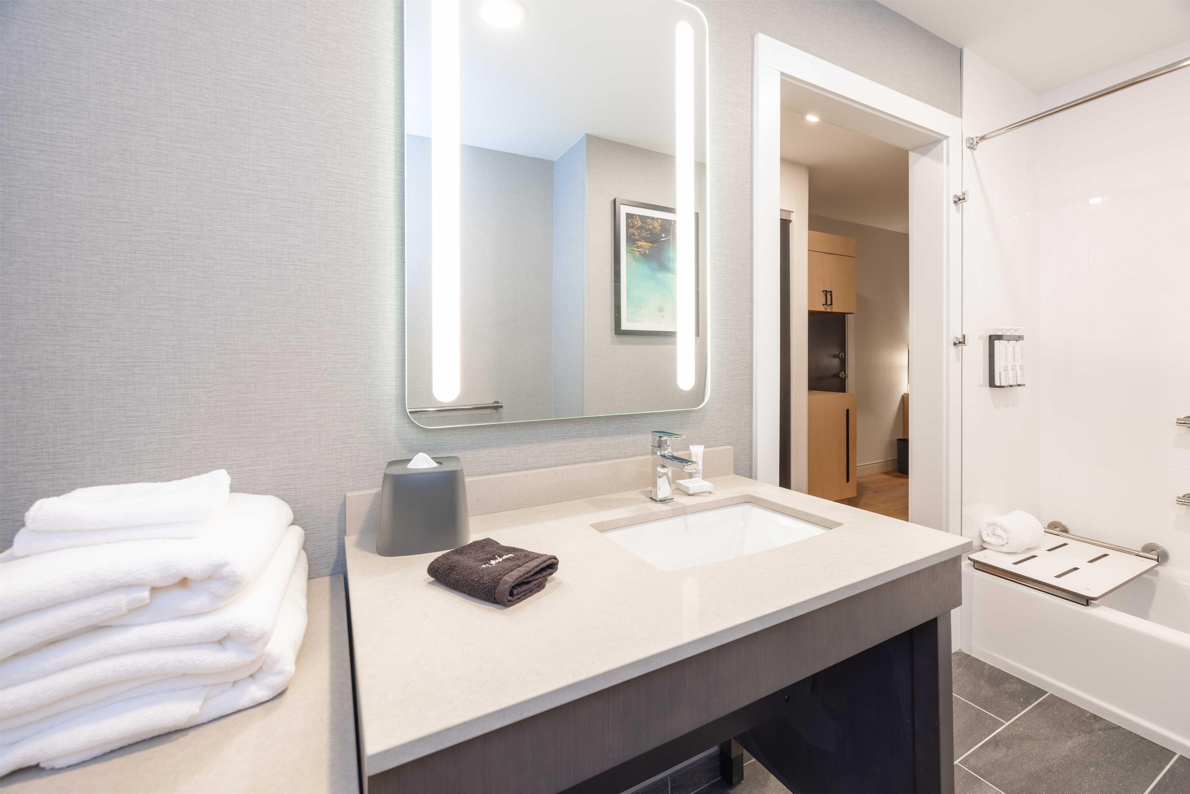 A modern bathroom with a large mirror, a sink, and a towel rack.