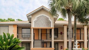 A multi-story hotel with a central courtyard, featuring a decorative fountain, palm trees, and potted plants. - Quality Inn near Manatee Springs State Park (Chiefland)