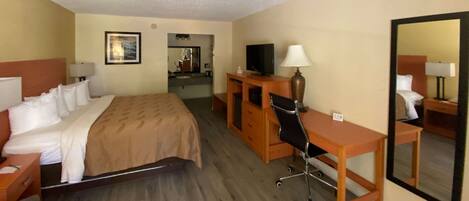 A hotel room with a bed, desk, chair, TV, and a mirror.