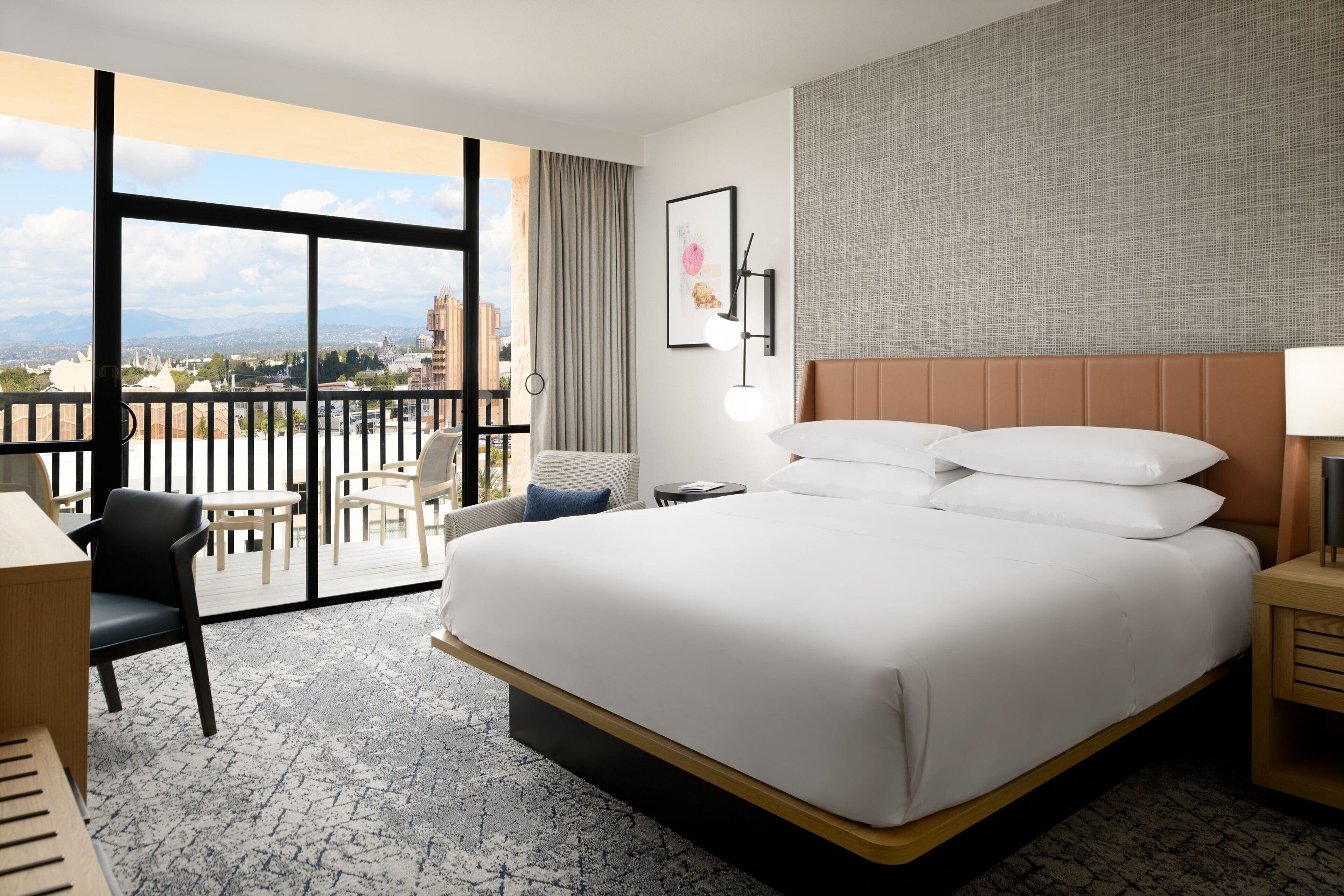 Habitación de hotel con una cama grande, un escritorio, una silla y vistas de la ciudad.